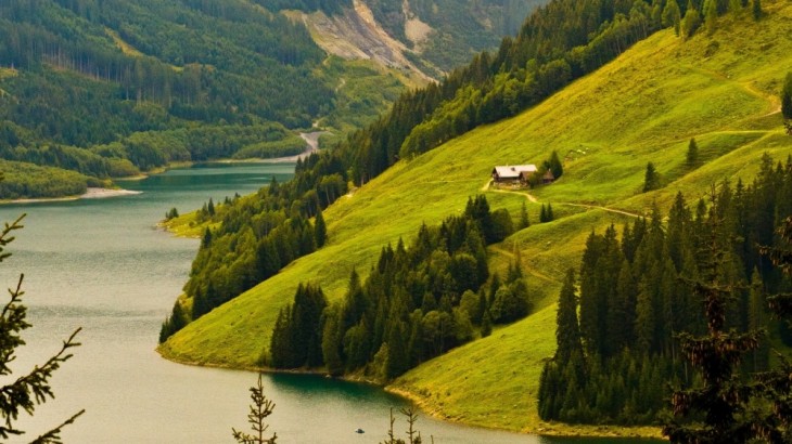 Casa en medio de pastos verdes cerca de un lago 