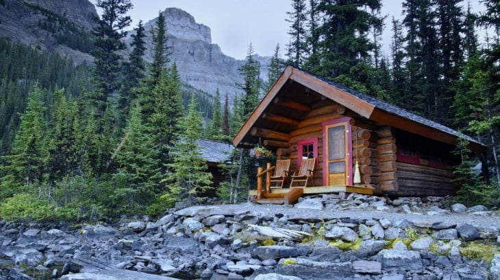 Casa de madera con pinos y montañas en su alrededor 