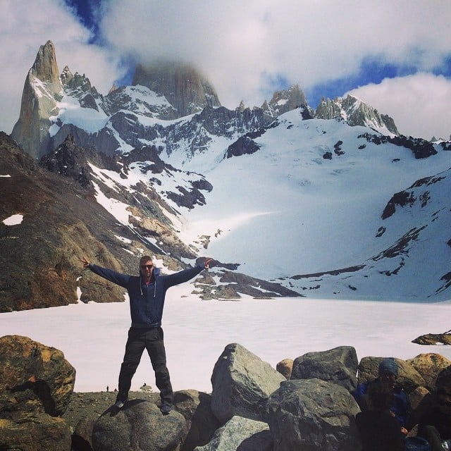 Un chico con las manos extendidas a los lados en unas montañas nevadas 