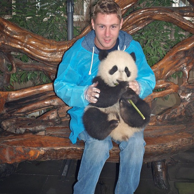 Johnny Ward con un panda en su piernas durante su viaje en China 