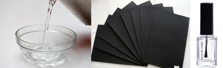 Imagen con un recipiente de agua, papel negro y esmalte transparente 