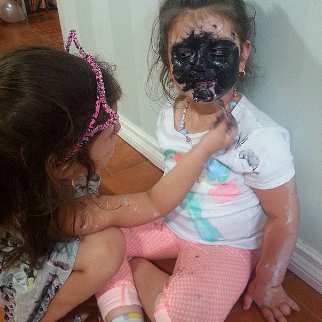 Niña pintando la cara de negro de otra niña 