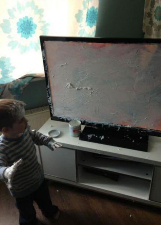 Niño frente a un mueble con una televisión llena de crema 