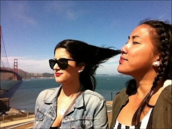 fotografía de una chica que parece estar respirando el cabello de su amiga 