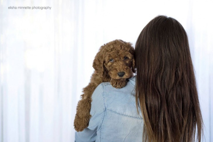 Mujer cargando a un perro con la cabeza recargada en su hombro. 