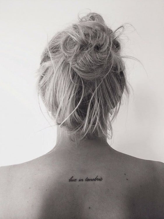 Tatuaje en la espalda de una mujer con la frase: "Lux in tenebris"
