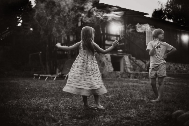 niña dándose vueltas frente a un niño en el jardín de una casa 