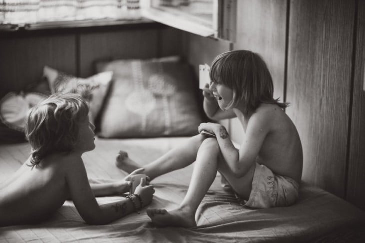 Dos niños jugando y platicando encima de una cama 