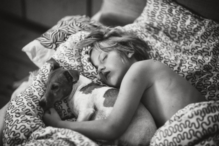 Niño acostado dormido abrazado de un perro 
