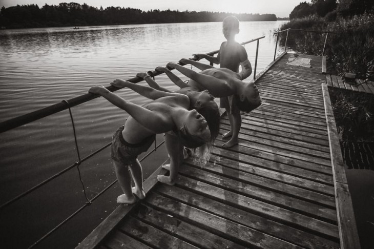 Niños en un puente colgados de un tubo inclinándose hacia atrás 