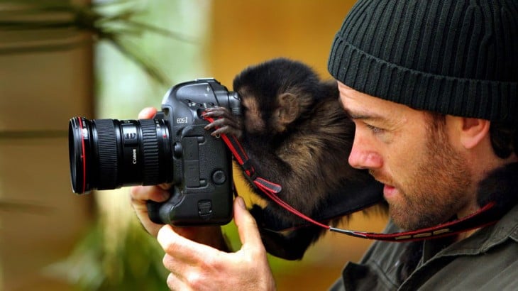 Fotógrafo junto a un pequeño chango detrás de una cámara tomando una foto 