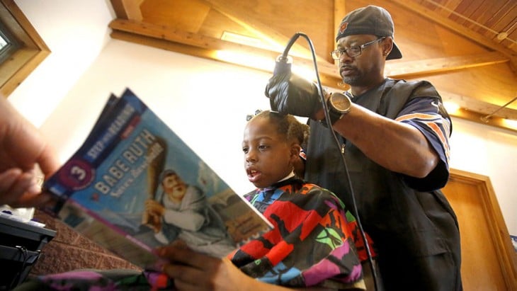 peluquero corta cabello a niños a cambio de que le lean una historieta