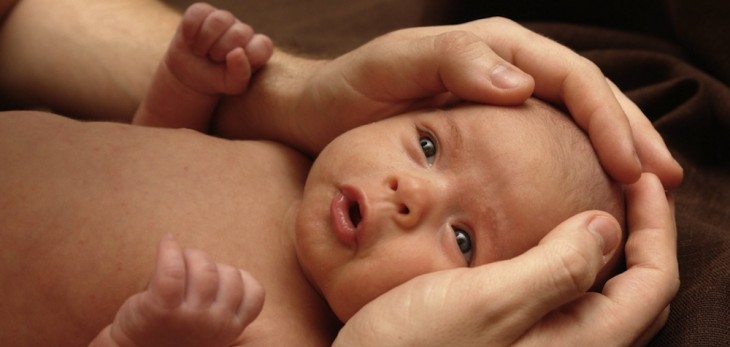 niño con la cara de sorprendido en los brazos de su mama