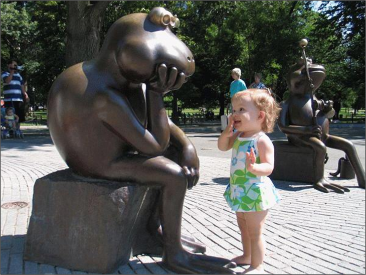 niña platicando con una rana estatua