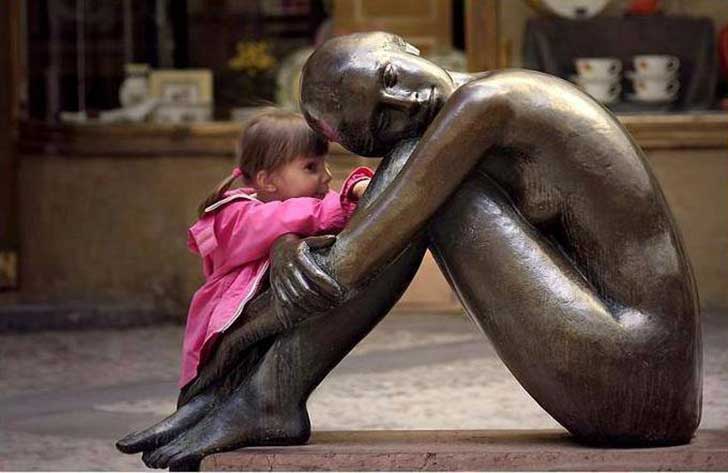 niña contandole un secreto a la estatua