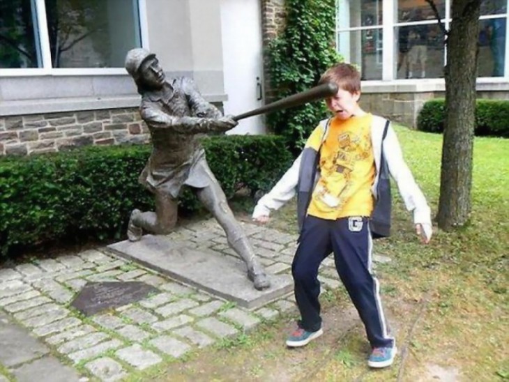 niño simulando que la estatua le pega con un bate