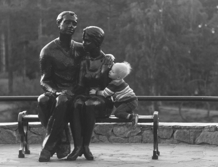 niño abranzando a una pareja de estatuas