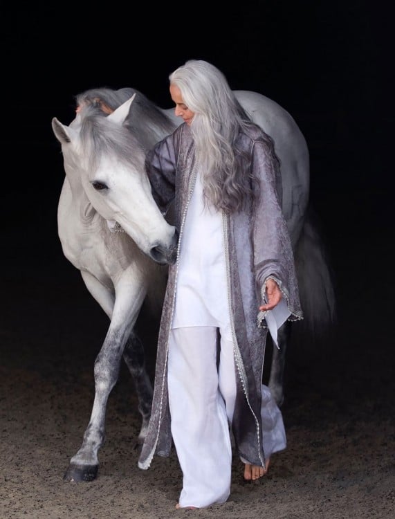 Rossi la modelo francesa de 59 años caminando junto a un caballo blanco 