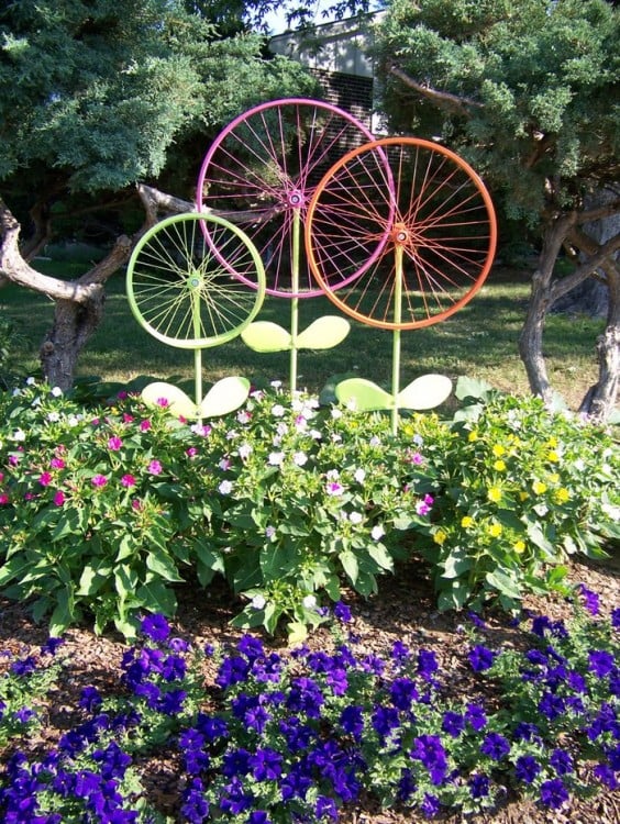 Jardín decorado con ruedas de bicicleta pintadas que simulan ser unas flores 