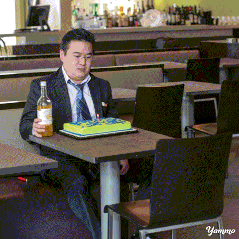Gif de un chico sentado frente a un pastel con un pingüino saliendo de su bolsillo 