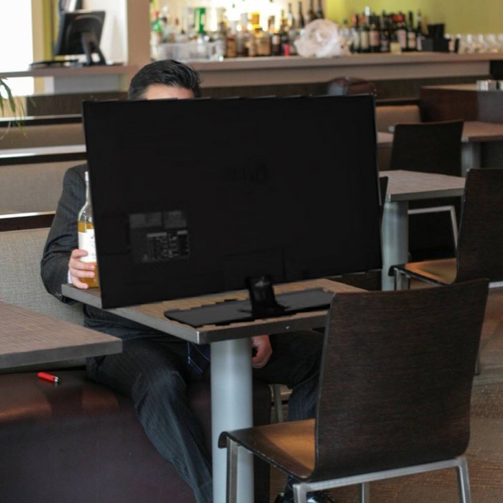 photoshop de un chico sentado frente a la mesa de un bar con una computadora frente a él 