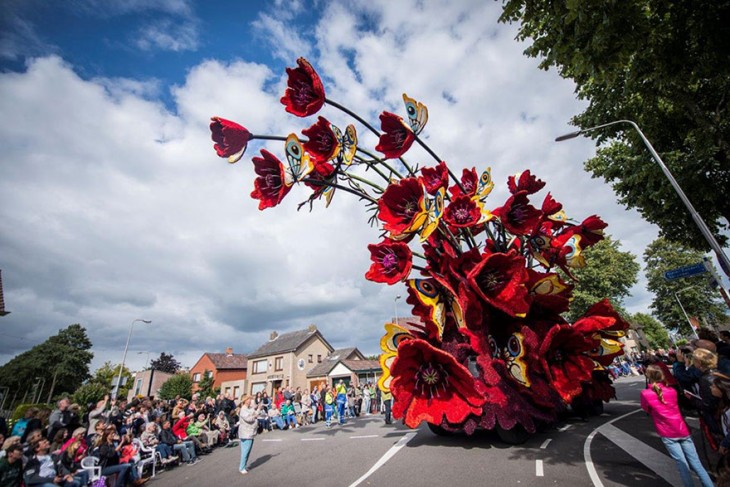 Carro en medio de un desfile con figuras de flores hechas con Dahlias 