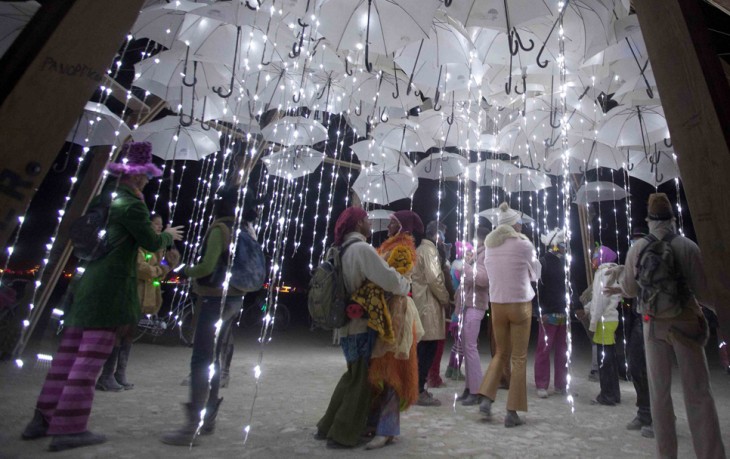 Personas debajo de muchas sombrillas blancas con luces en el festival Burning Man 