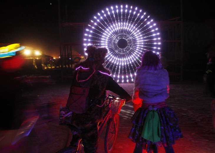 dos chicos en bicicleta observando unas luces en forma de círculo 
