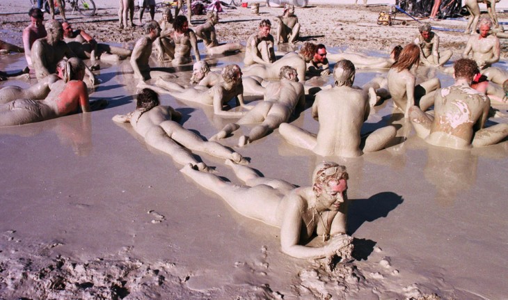 Personas en el festival Burning Man acostado en el suelo llenos de lodo 