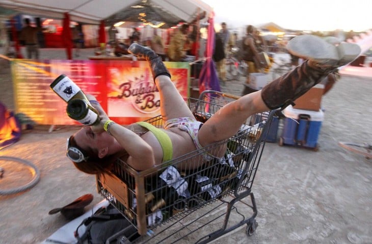 Mujer sobre un carrito de super tomando vino en el festival Burning Man 