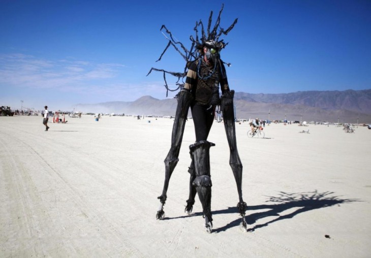 Hombre con brazos y manos grandes hechas con un material negro en el festival Burning -man 