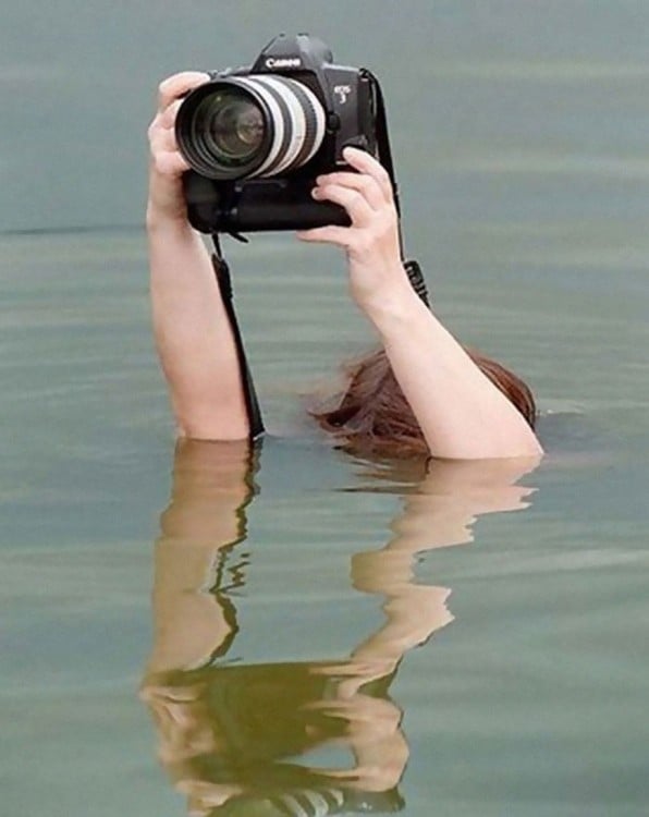 Manos de una persona sumergida en el agua tomando una fotografía 