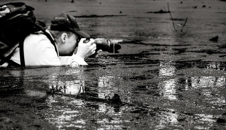 Hombre tomando una fotografía dentro de un lago a blanco y negro 