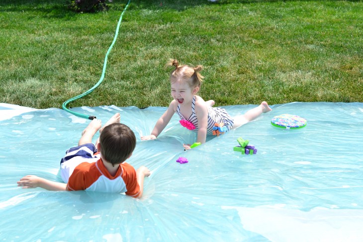 una niña y un niño acostados sobre un colchón de agua en el jardín 