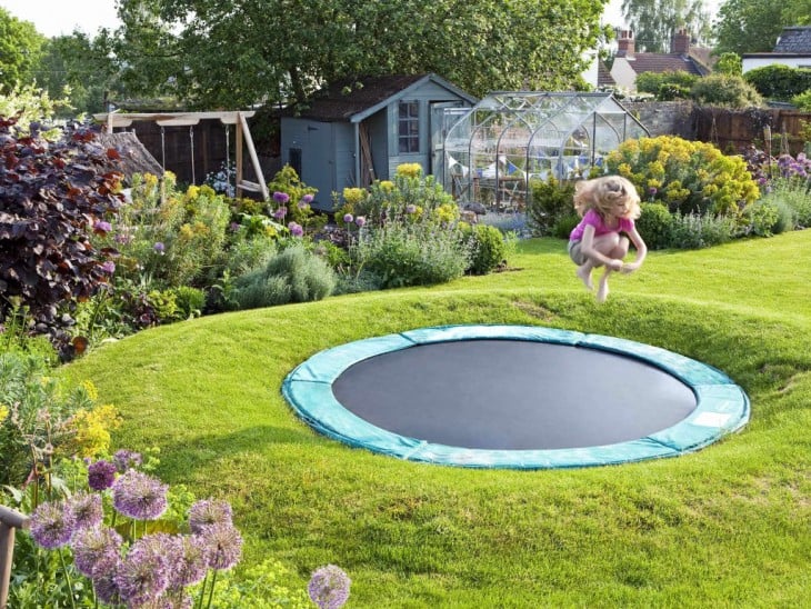 Niña saltando en un trampolín en el jardín 