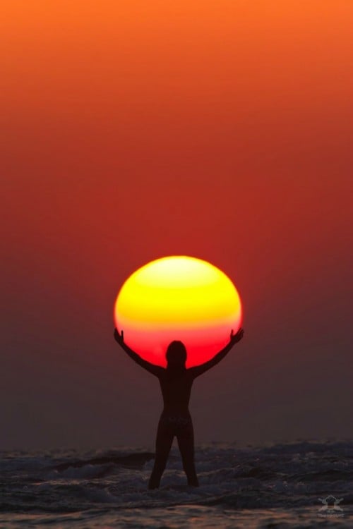 fotografía a contra luz de una persona sosteniendo el sol en un atardecer 