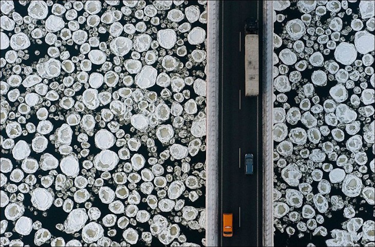 fotografía de carros pasando por un puente sobre agua con hielo 