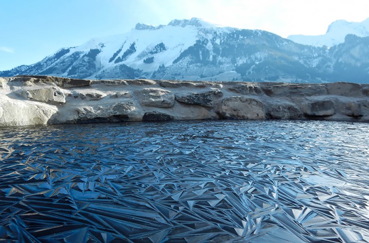 Paisaje de una laguna congelada en Suiza con montañas a lo lejos