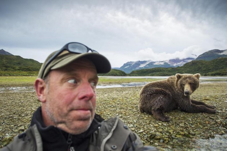 hombre tomando un selfie con un oso detrás de él 