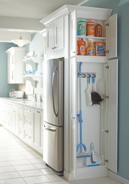 Muebles de una cocina con un pequeño gabinete al costado del refrigerador para guardar los productos de limpieza