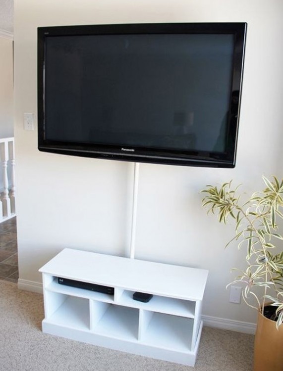 Mueble blanco con un tubo sosteniendo una televisión cerca de una pared 