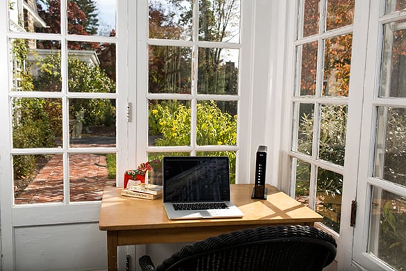Escritorio con una computadora y un módem cerca de una ventana 