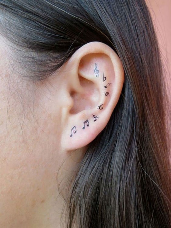 tatuaje de notas musicales en la oreja