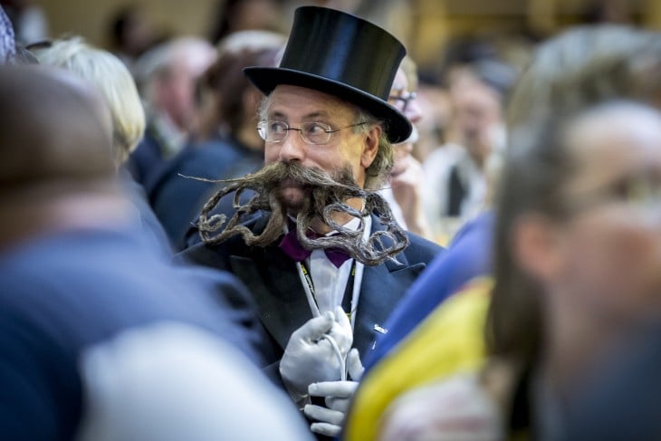 fotografía de un hombre con barba y bigote largo en medio de muchas personas 