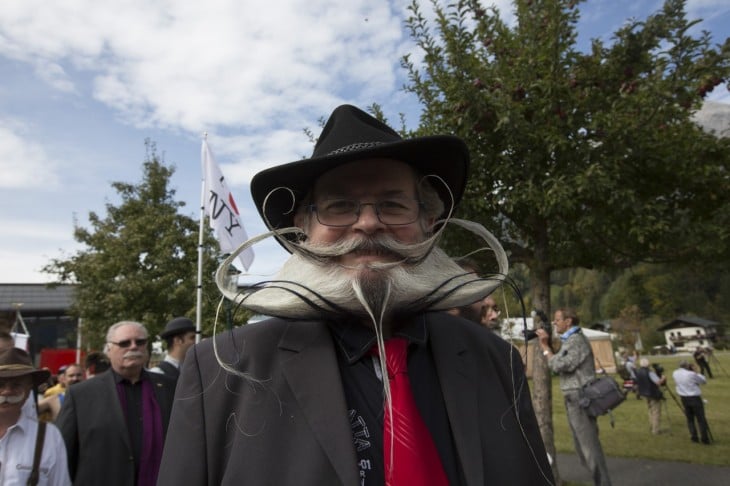 Hombre con sombrero y una gran barba peinada hacia arriba 