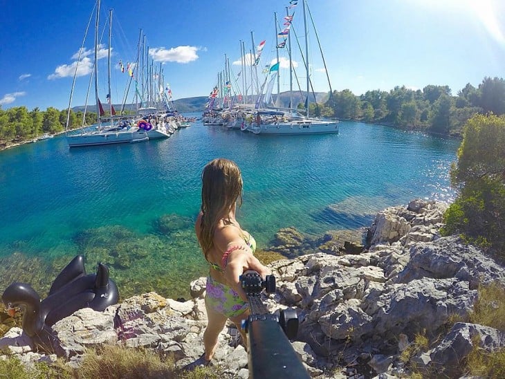 Selfie de una chica frente a unos barcos a la orilla de un rió 