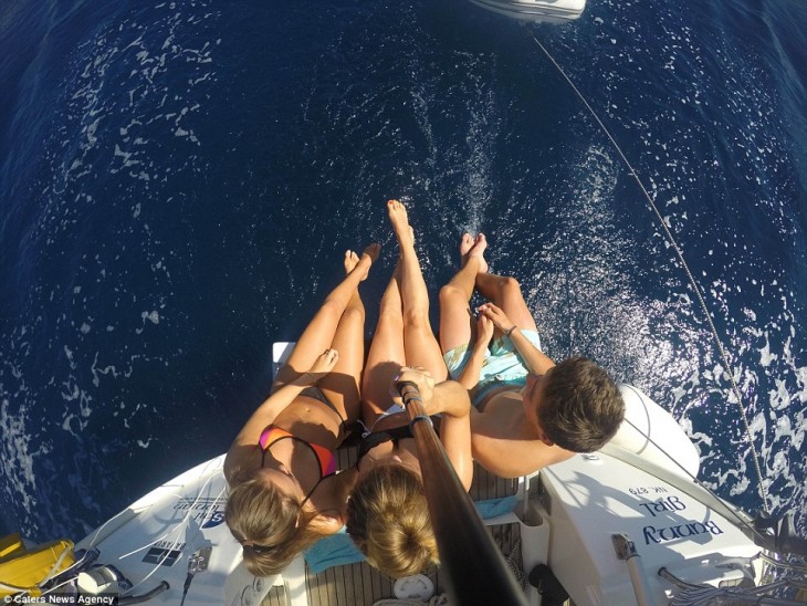 selfie de tres chicas sentados a la orilla de un bote viendo hacia el mar 