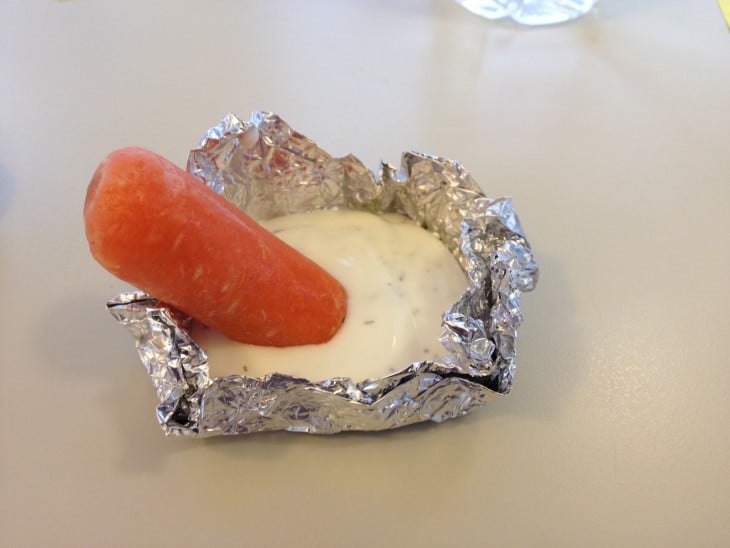 un pedazo de papel aluminio con aderezo ranch y una zanahoria encima 