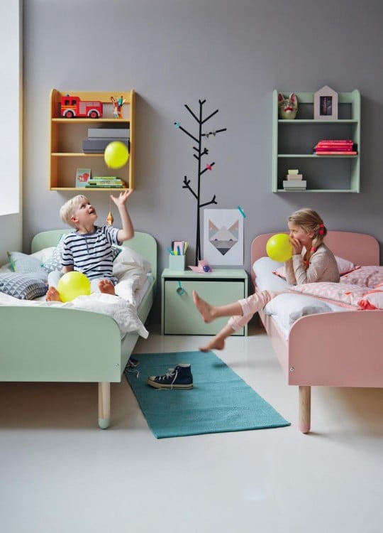 dos niños en una habitación con dos camas lleno de juguetes 
