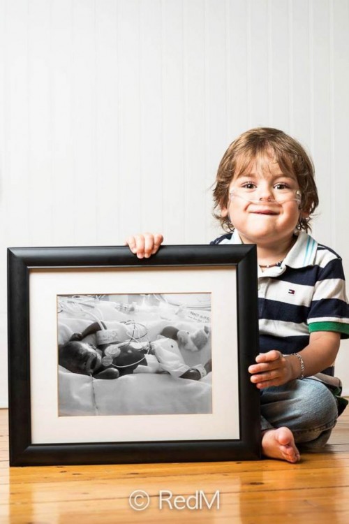 Niño sentado en el suelo sosteniendo un retrato a un costado de él 